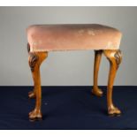 EARLY TWENTIETH CENTURY CARVED WALNUT STOOL, the oblong top covered in pink and floral fabric, and