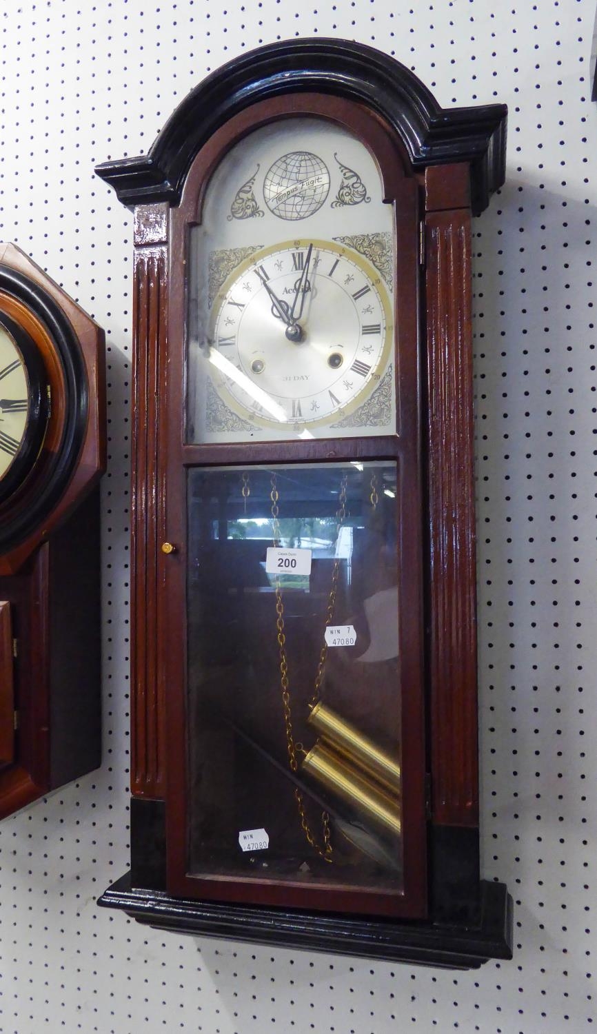 A WALL CLOCK WITH BRASS CASED WEIGHTS AND ROMAN DIAL INSCRIBED 'ACCTIM' 31 DAY MOVEMENT, 30 1/2"