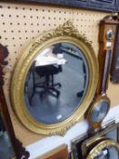 A LATE VICTORIAN/EDWARDIAN OVAL BEVELLED WALL MIRROR IN GILT GESSO FRAME WITH FLORIATED CRESTING AND