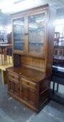 AN ERCOL DISPLAY CABINET, THE TOP HAVING TWO GLAZED DOORS, THE LOWER SECTION HAVING TWO DRAWERS OVER
