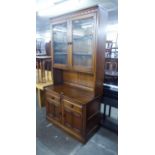 AN ERCOL DISPLAY CABINET, THE TOP HAVING TWO GLAZED DOORS, THE LOWER SECTION HAVING TWO DRAWERS OVER