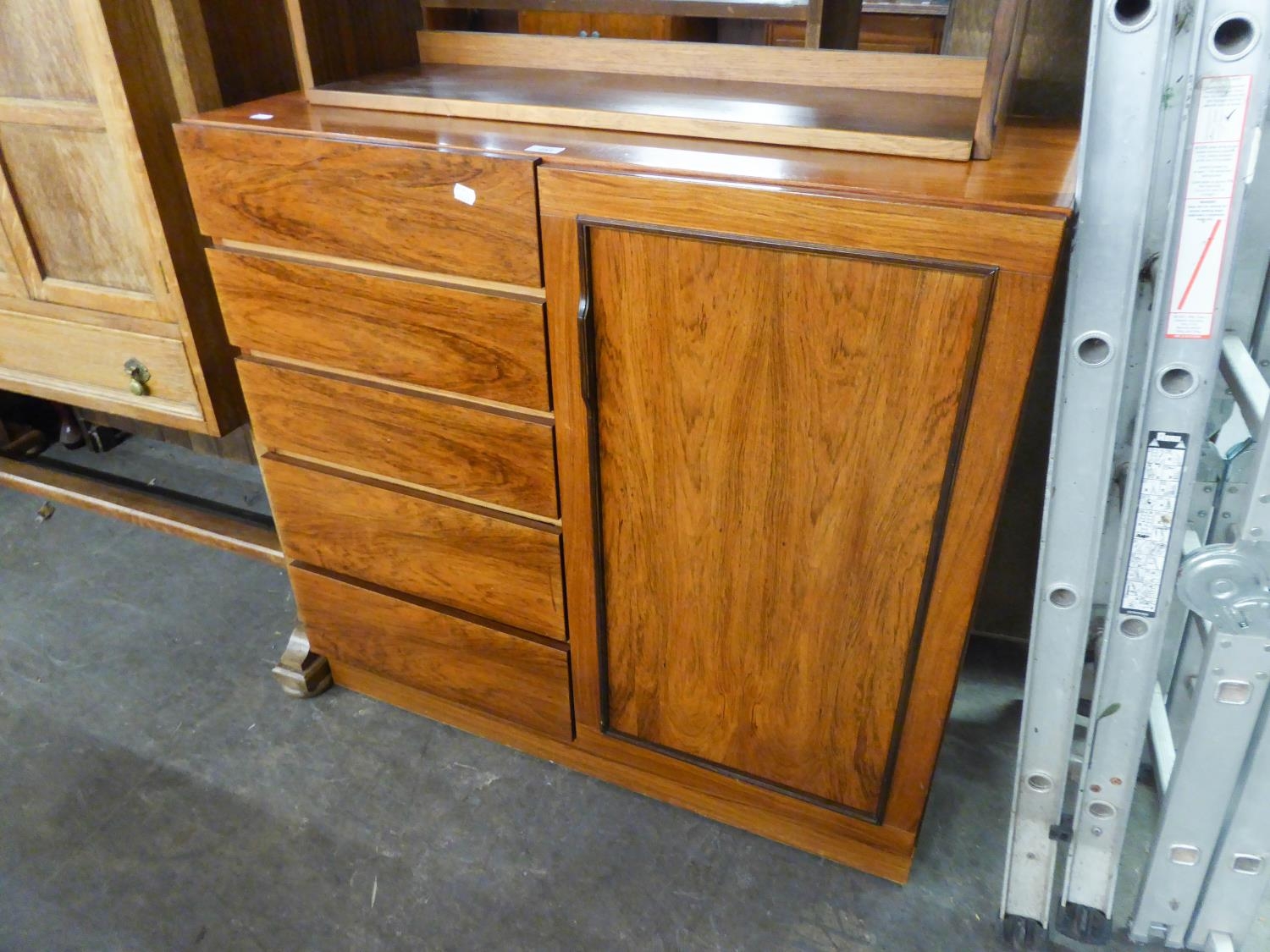 A MODERN HARD WOOD CHEST WITH A NEST OF FIVE SHORT DRAWERS ALONGSIDE A SINGLE DOOR CUPBOARD, ON