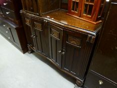 AN 1930's OAK SIDEBOARD, HAVING SHAPED FRONT AND FOUR DOORS WITH CARVED DECORATION