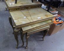 NEST OF THREE CAST BRASS AND ONYX COFFEE TABLES, RAISED ON CABRIOLE SUPPORTS (damage to the top)