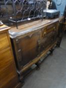 A 1930's OAK JACOBEAN REVIVAL CANTED FRONT SIDEBOARD
