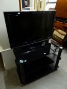 A PANASONIC 32" FLAT SCREEN TV AND REMOTE ON A THREE TIER BLACK GLASS STAND