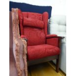A MODERN POLISHED WOOD FIRESIDE ARMCHAIR, COVERED IN EMBOSSED CRIMSON MOQUETTE