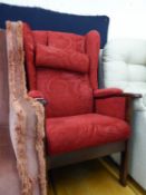 A MODERN POLISHED WOOD FIRESIDE ARMCHAIR, COVERED IN EMBOSSED CRIMSON MOQUETTE