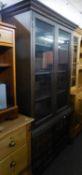 YOUNGER FURNITURE ELM DISPLAY CABINET ENCLOSED BY TWO GLAZED DOORS, FREE-STANDING ON AN ADVANCED