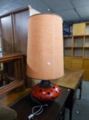 A LARGE PIERCED RED GLAZED POTTERY SQUAT CIRCULAR FLOOR LAMP, WITH TALL ORANGE FABRIC SHADE