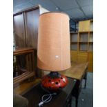 A LARGE PIERCED RED GLAZED POTTERY SQUAT CIRCULAR FLOOR LAMP, WITH TALL ORANGE FABRIC SHADE