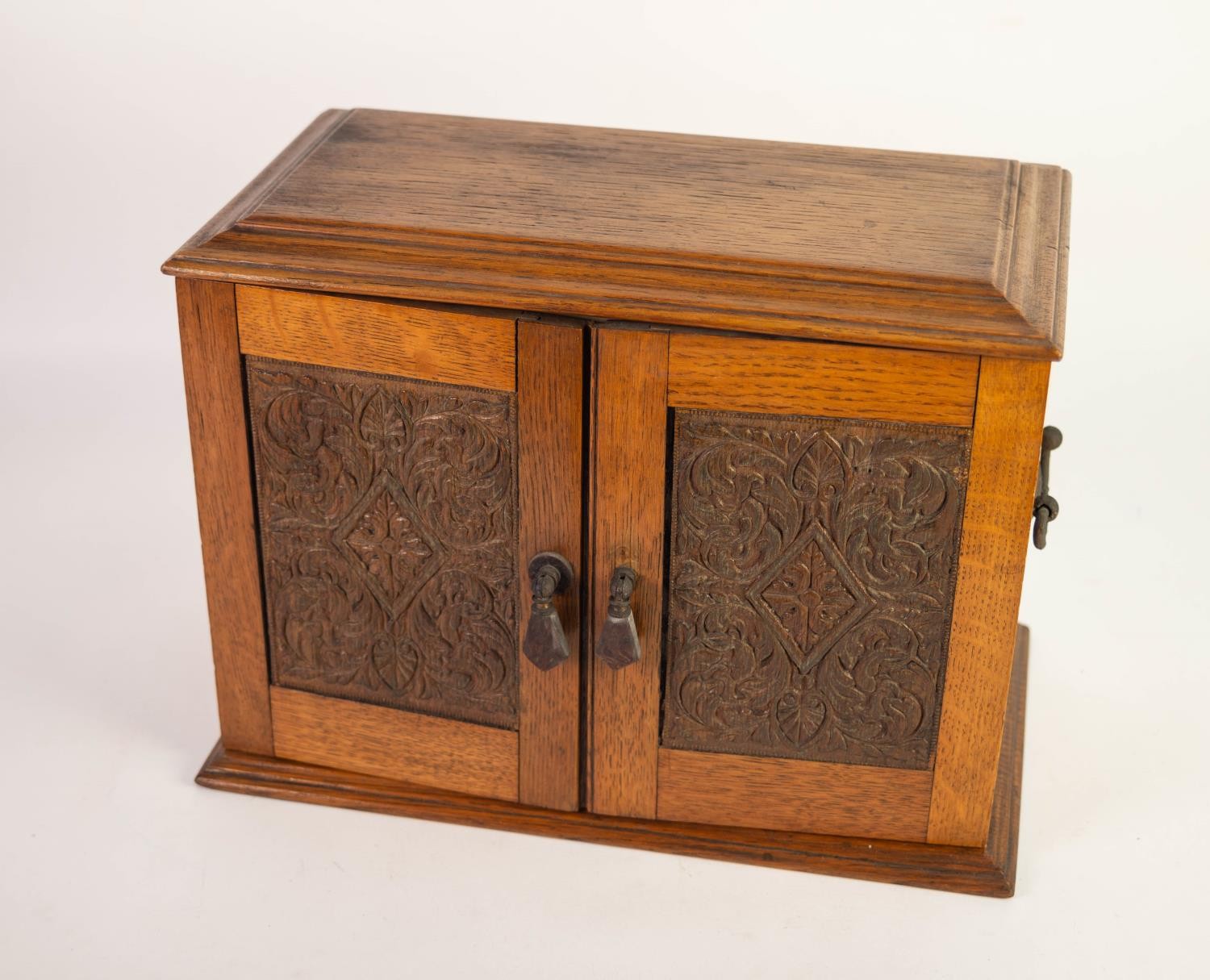 CIRCA 1920s CARVED OAK TWO DOOR SMOKER'S CABINET with hinge opening top, later fitted with four