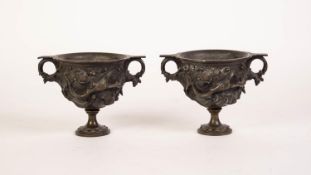 PAIR OF NINETEENTH CENTURY CAST BRONZE TWO HANDLE PEDESTAL SIDE VASES, cup shaped bowls with high