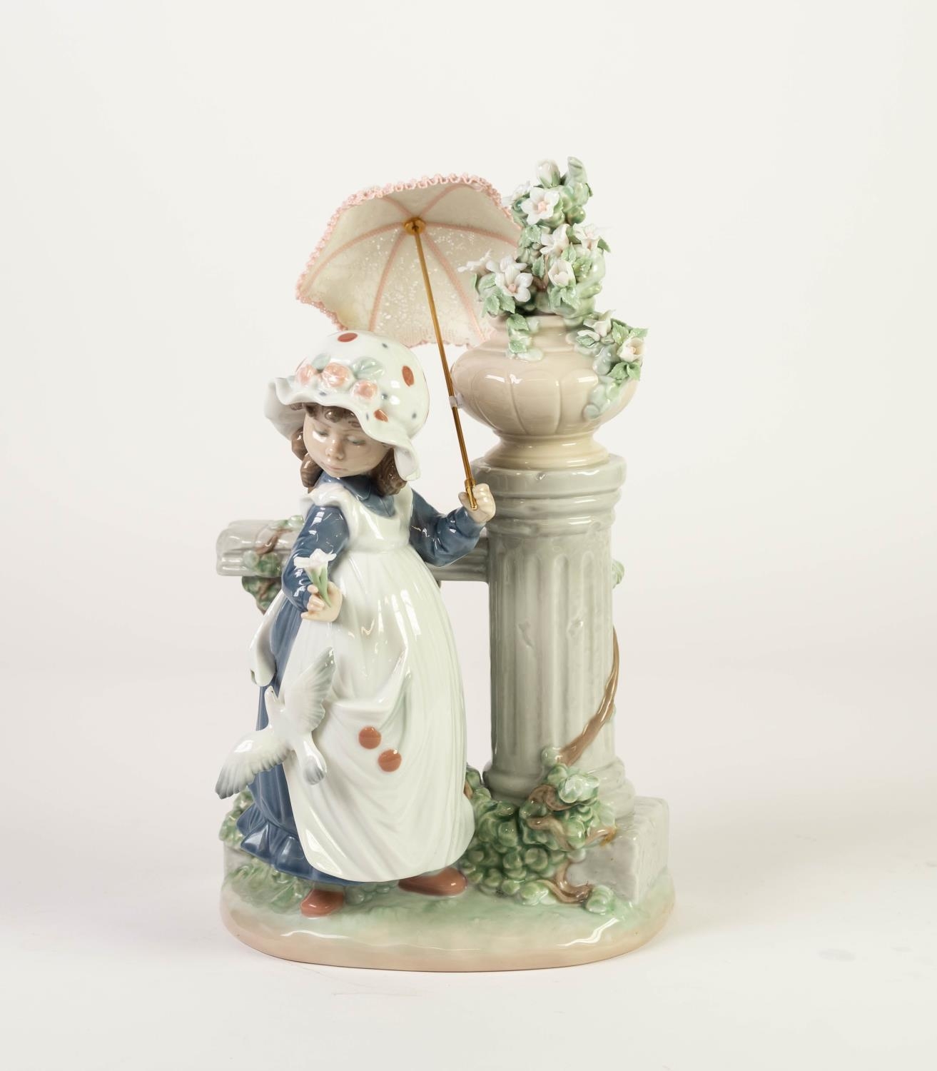 LLADRO PORCELAIN MODEL OF A LITTLE GIRL beside a garden flower filled pedestal urn, with a parasol