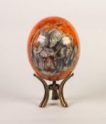 ORANGE LUSTRE GLAZED OSTRICH EGG, decorated with African wild animals, 6 ½? (16.5cm) high, on a gilt