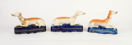 THREE VICTORIAN STAFFORDSHIRE POTTERY RECUMBENT GREYHOUND MANTEL SHELF SPILL RECEIVERS, (one damaged