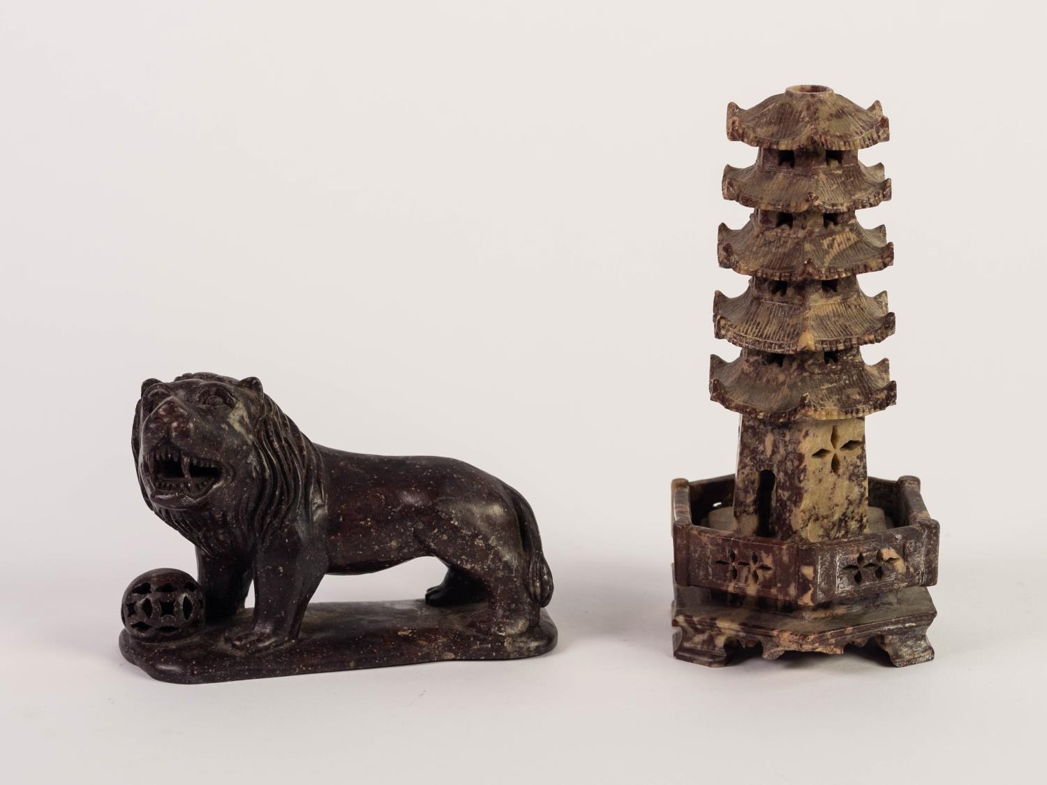 CHINESE CARVED DARK RED SOAPSTONE MODEL OF A TEMPLE DOG, Modelled with brocade ball at its feet,
