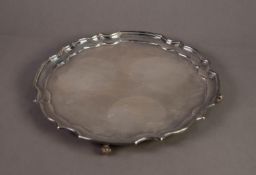 20th CENTURY SILVER WAITER with pie-crust border, standing on four volute-scroll feet, hallmarked