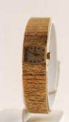 18ct GOLD OMEGA LADY'S WRISTWATCH, baton numerals, on integral bark textured strap, 48.9 grms gross