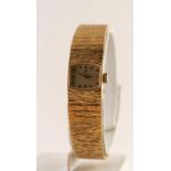 18ct GOLD OMEGA LADY'S WRISTWATCH, baton numerals, on integral bark textured strap, 48.9 grms gross