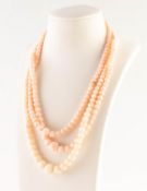 A PALE CORAL BEAD TRIPLE STRAND NECKLACE with gilt metal clasp