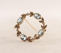 9ct GOLD CIRCLET OR WREATH PATTERN BROOCH set with four oval blue zircons and four seed pearls, 1