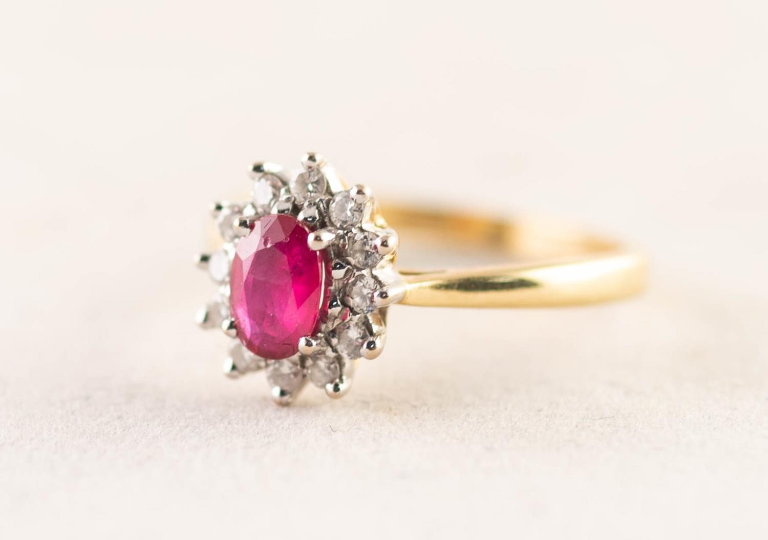 18ct GOLD, RUBY AND DIAMOND OVAL CLUSTER RING set with an oval centre ruby and surround of twelve