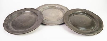 THREE SIMILAR ANTIQUE PEWTER CHARGERS, one having London touch marks to the broad top rim, 15in (