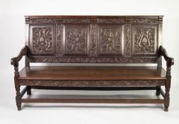 NINETEENTH CENTURY CARVED OAK SETTLE, the four panel back carved with stylised masks and Pine cone