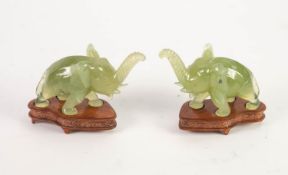 CASED PAIR OF FAR EASTERN CARVED GREEN HARDSTONE MODEL ELEPHANTS, on wire inlaid wooden stands