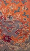 CHINESE NEEDLEWORK ORANGE/RED SILK PANEL, worked in colours with a detailed design of a snarling