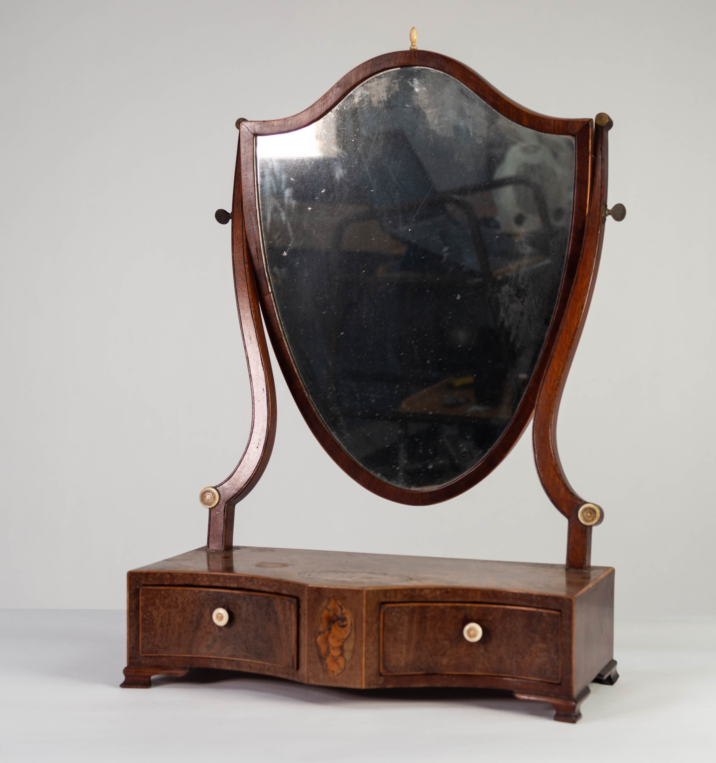 LATE GEORGIAN INLAID MAHOGANY TOILET MIRROR, the shield shaped plate within a crossbanded frame with