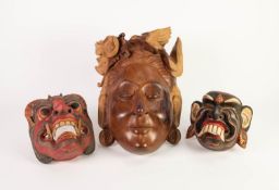 THREE MODERN FAR EASTERN CARVED WOOD WALL MASKS, the larger in natural wood, of a female with a bird