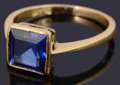 A delicate single stone square shaped step cut synthetic sapphire ring,