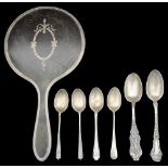 A George V silver mounted tortoiseshell hand mirror and various silver spoons.
