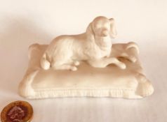 MINTON STYLE FIGURE OF RECUMBANT SPANIEL ON A TASSLED CUSHION, IMPRESSED MARK TO BASE, SIMILAR TO