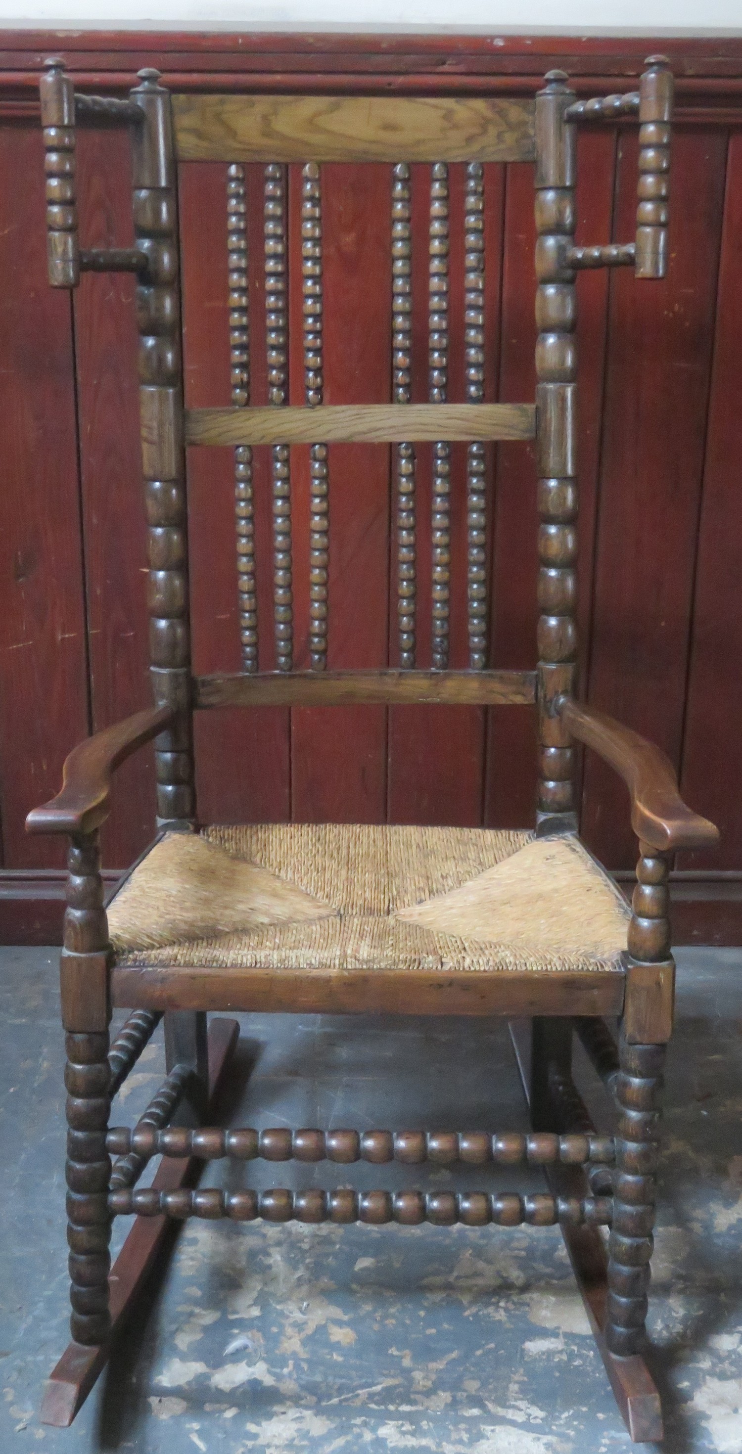 Late 19th / early 20th century rush seated oak bobbin decorated rocking chair. Approx. 107cms H x