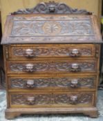 Late 19th / early 20th century heavily carved fronted oak fall front writing bureau, with fitted