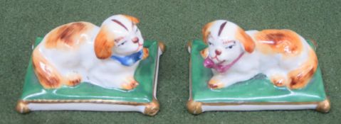 Pair of small late 19th/ early 20th century ceramic figures, depicting recumbent dogs on cushions,