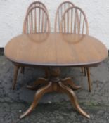 Ercol mid 20th century oak extending dining table, with four stick back chairs to accord. Approx.