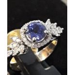 An 18ct white gold ring set with a brilliant cut tanzanite and diamond set shoulders, (N.5).