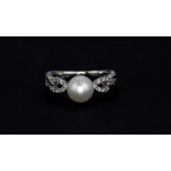 A 9ct white gold pearl set ring with diamond set shoulders, (N.5).