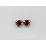 A pair of 18ct white gold earrings set with heart cut rubies surrounded by diamonds, L. 0.6cm.