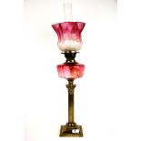 A Victorian gilt brass and cranberry glass oil lamp, H. 74cm. Condition: shade A/F.