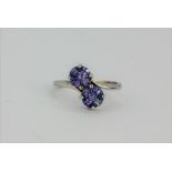 A 9ct white gold tanzanite set crossover ring, (M.5).