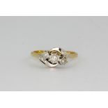 An 18ct yellow gold and platinum three diamond set crossover ring, (J.5).