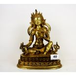 A Tibetan gilt bronze figure of a seated Buddha, H. 25cm. Holding a sacred bell in his left hand and
