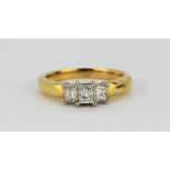 An 18ct yellow and white gold ring set with three princess cut diamonds, approx. 0.75ct, (O.5).