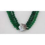 A triple row polished jade bead necklace on a carved mother of pearl clasp, L. 44cm.