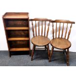 An oak bookcase, a circular coffee table and two country chairs.